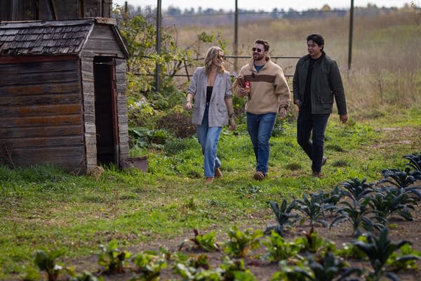Three people walk through a farmstead film set