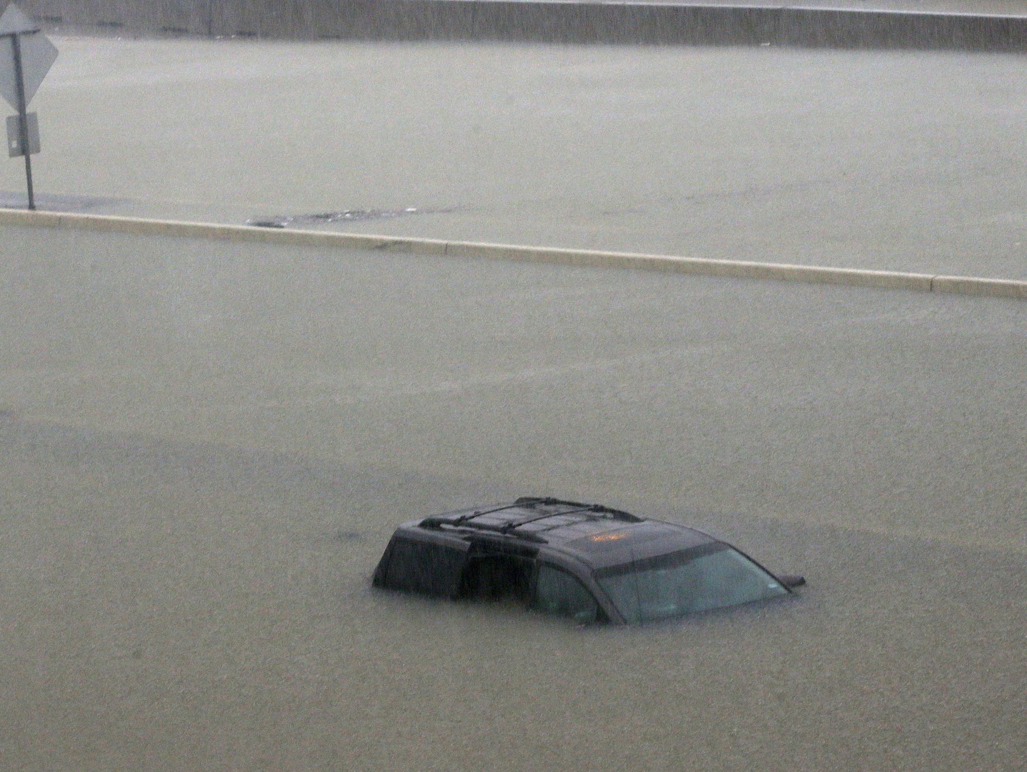 An abandoned vehicle sits in flood waters on the I-10 highway