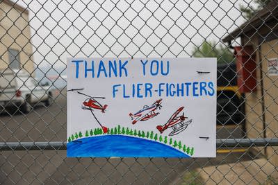 a sign thanking fire fighters hangs on a fence