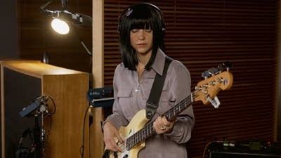 A musician plays bass in a recording studio