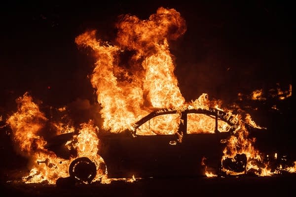 Flames from the Kincade Fire consume a car
