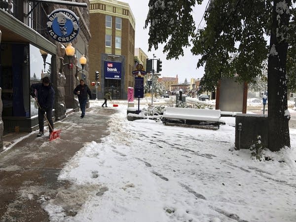 People clear the sidewalk after a fall snowstorm in Montana.