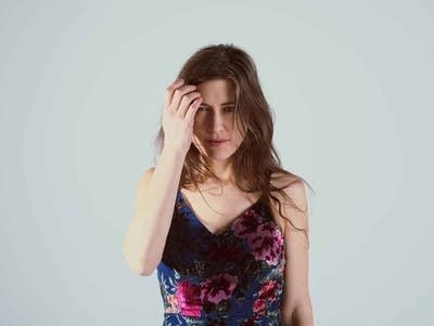 A woman brushes her hair back while posing for a studio portrait