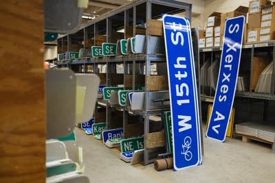 Two blue street signs sitting in sign shop
