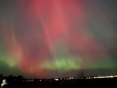 Green and red aurora lights in the night sky.