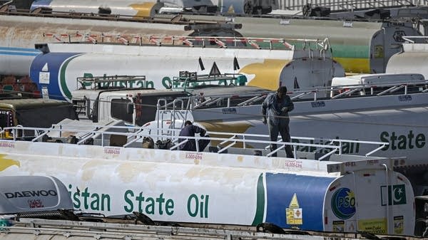 Workers stand on top of an oil tanker parked near an oil storage terminal in Karachi, Pakistan. The country is facing unprecedentedly high fuel prices.