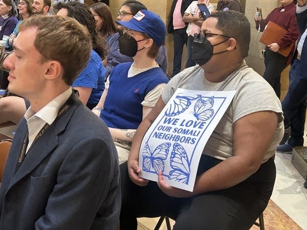 Event attendees hold signs reading "We love our Somali neighbors."