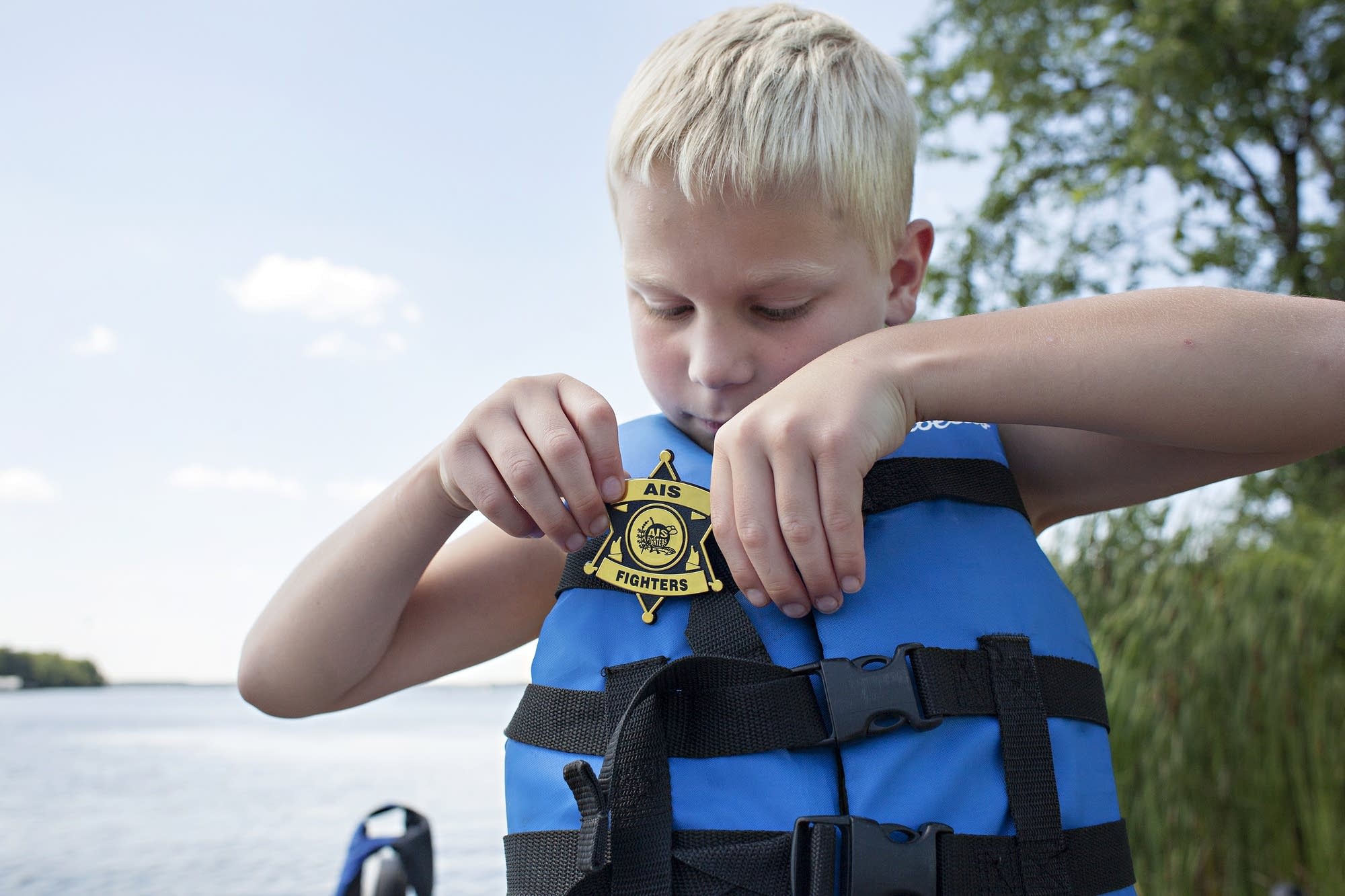 Gibbson Illg, 6, puts on a plastic badge before heading out to fish.