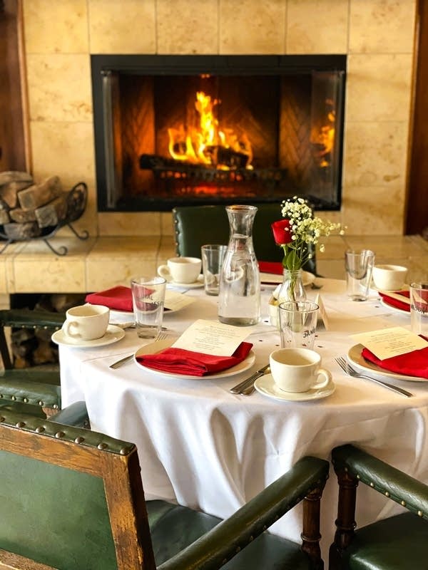 A fireplace and a table set for dinning guests.