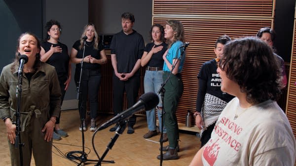 A large group of singers performing in a recording studio