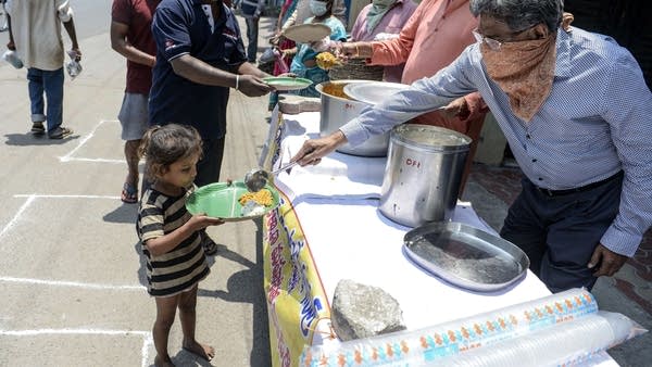 Dhanwantari Foundation International members serve food to homeless people on a street during a government-imposed nationwide lockdown as a preventive measure against the COVID-19 coronavirus, in Hyderabad, India, on April 9, 2020.