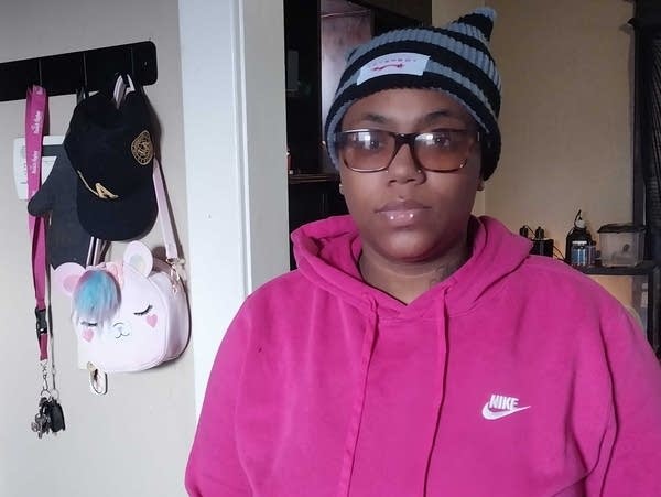 A woman in a pink sweatshirt stands in a home