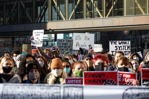 People hold signs behind a banner.