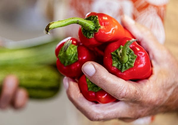 A man holds peppers and squash.