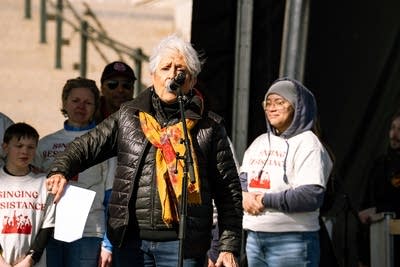 A large group of musicians perform on an outdoor stage at a huge rally