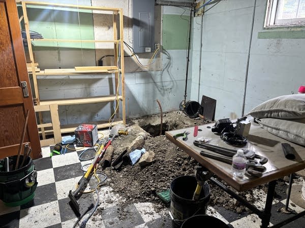 A shot of a basement, where a copper line is seen sticking out of the ground in the corner.