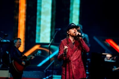 A musician sings onstage in a large arena