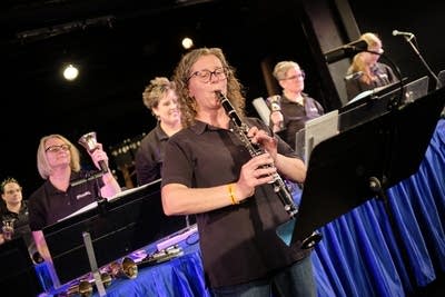 A clarinetist accompanies a bell ensemble performing onstage