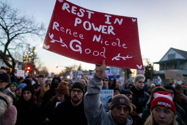 A person holds a red sign