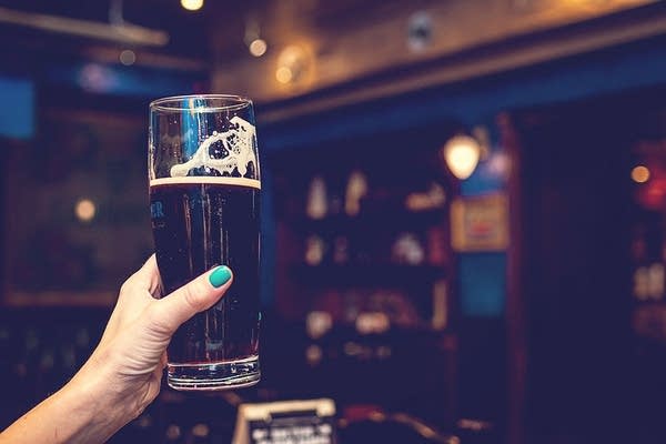 A woman raises a glass of beer.