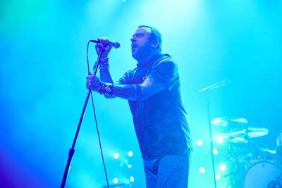 A musician sings onstage in a large music venue