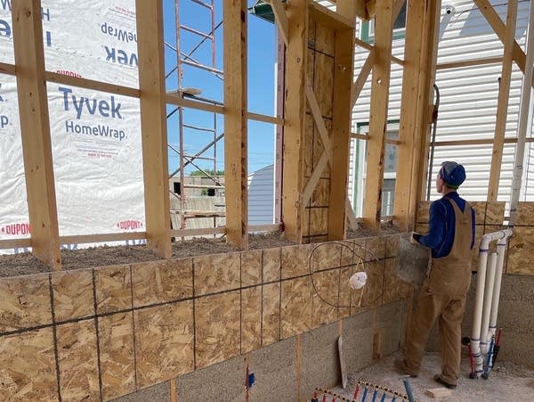 a worker stands next to a partially constructed wall 