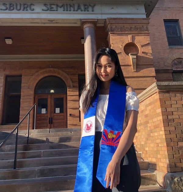 A young woman wearing a blue graduation sash with the Karen Nation flag. 