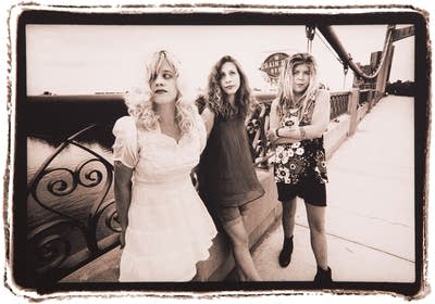 Three women pose for a photograph on a bridge.