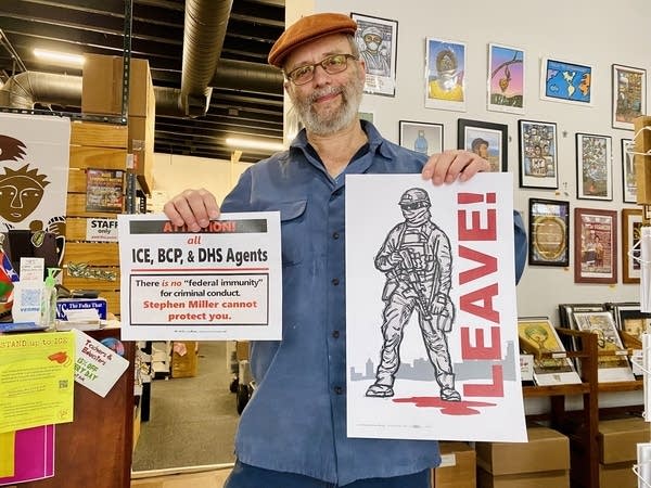 A man holds two signs up in a studio.
