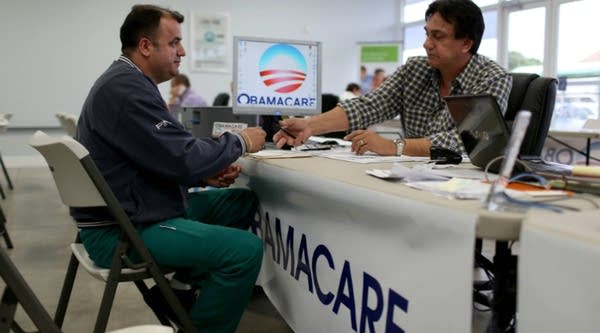 Ariel Fernandez (L) sits with Noel Nogues, an insurance advisor with UniVista Insurance company, as he signs up for the Affordable Care Act.