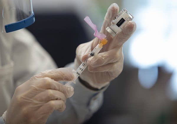 A close up of a needle going into a glass vial.