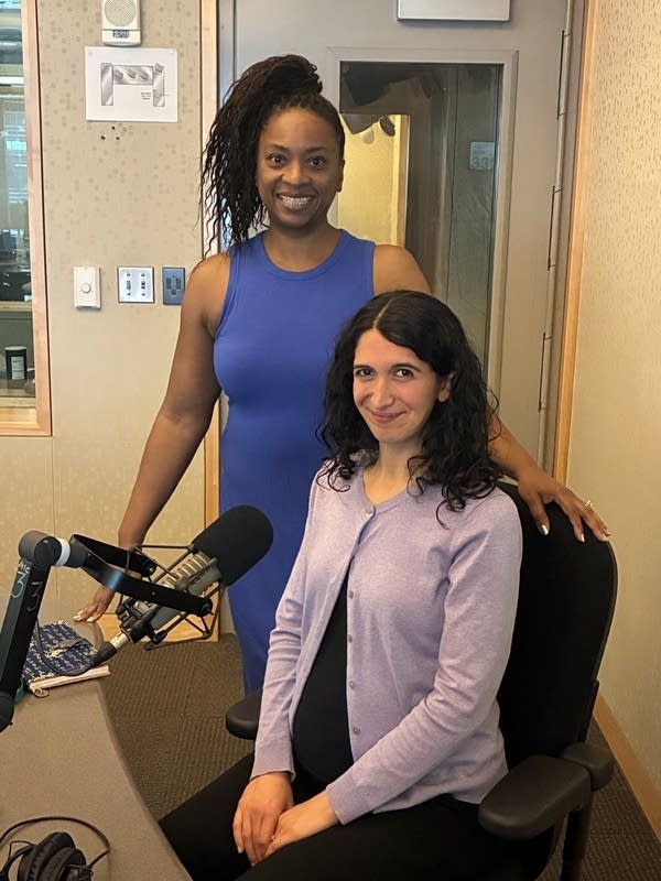 two women pose for a photo in a studio
