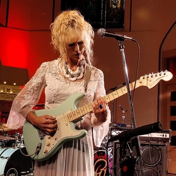 Mara Lovejoy plays an electric guitar.