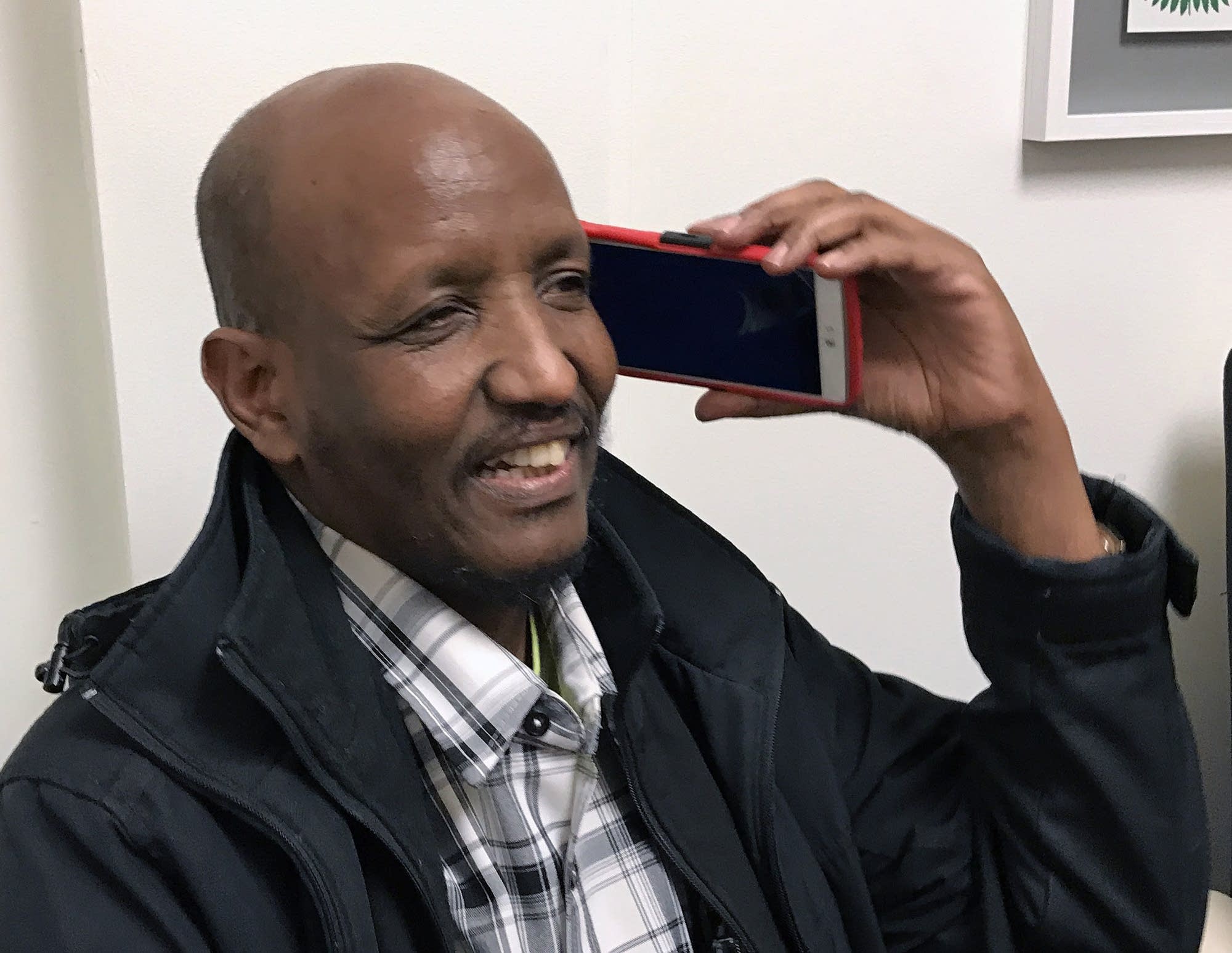 Mahamed Iye smiles as he speaks to his wife in Nairobi on his cell phone.