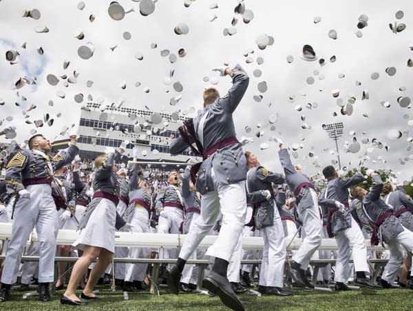 West Point cadets toss their caps into the air