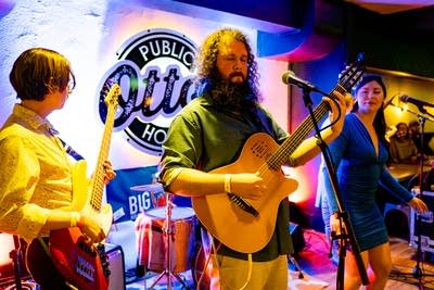 Three musicians performing onstage in a music venue