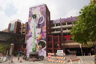 A photo of people working on a large mural on a side of a building.