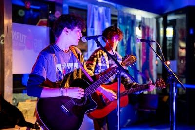 2 guitarists performing and singing on stage
