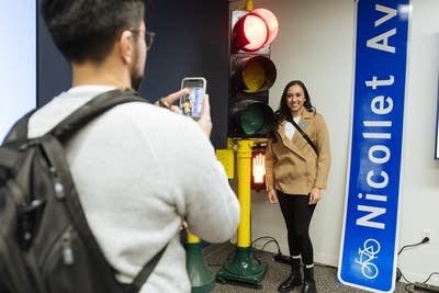 A man taking a picture of woman next to a traffic light and street sign