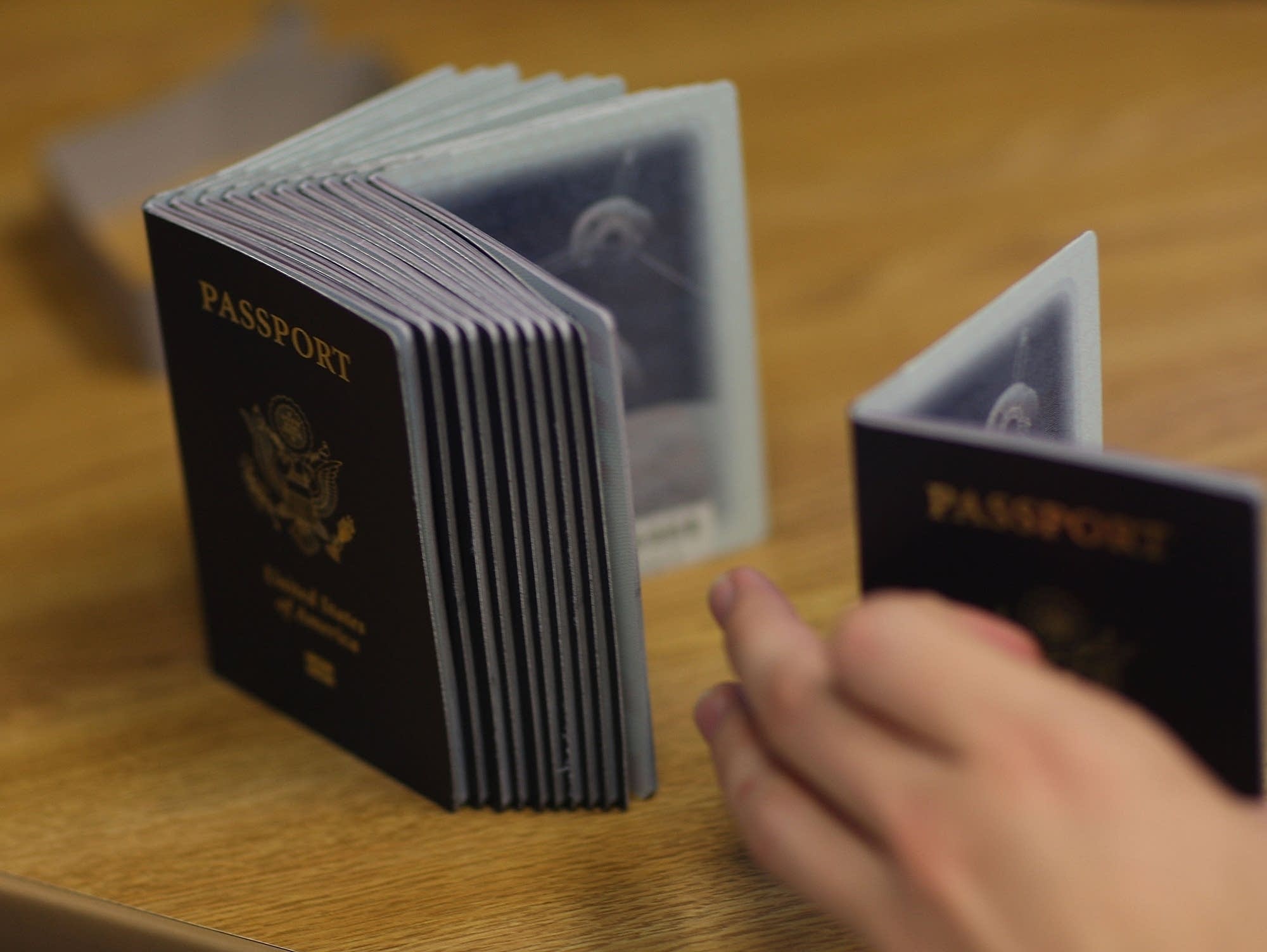 A Passport Processing employee uses a stack of blank passports