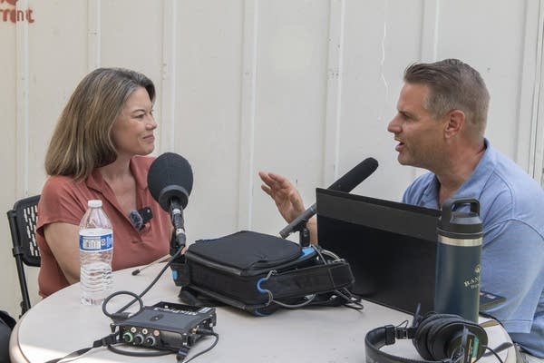 Two people sit for an interview with microphones.