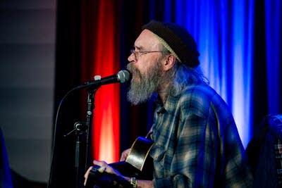 man playing acoustic guitar and singing on stage