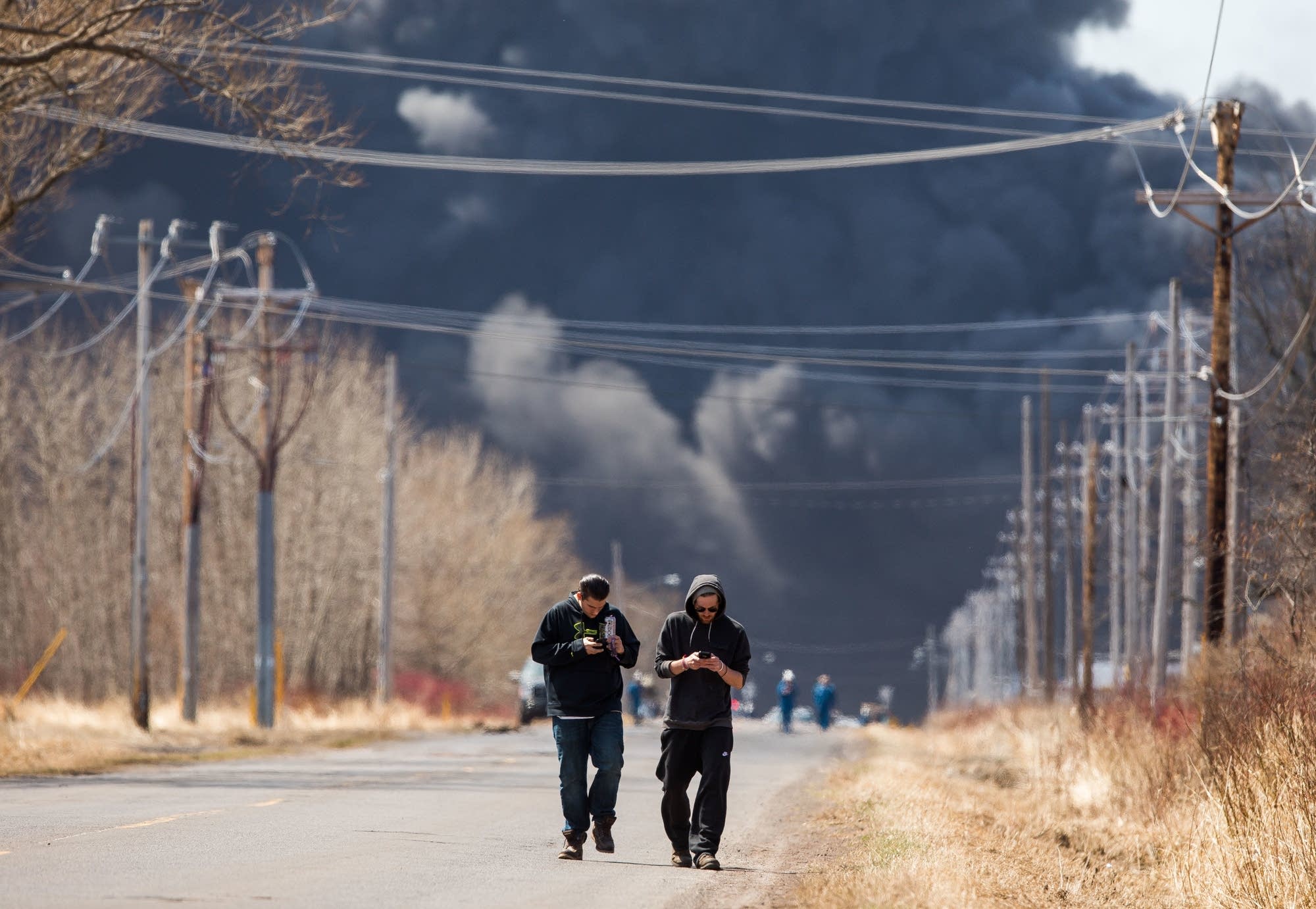 Two men walk away after capturing images of the smoke plume.
