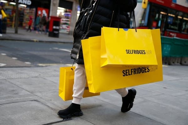 A shopper carries bags from department store Selfridges along Oxford Street on the Sunday afternoon in London on December 6, 2020. - Shoppers returned to Englands high streets this week as shops reopened following the end of a four-week coronavirus lockdown. (Photo by Hollie Adams / AFP) (Photo by HOLLIE ADAMS/AFP via Getty Images)
