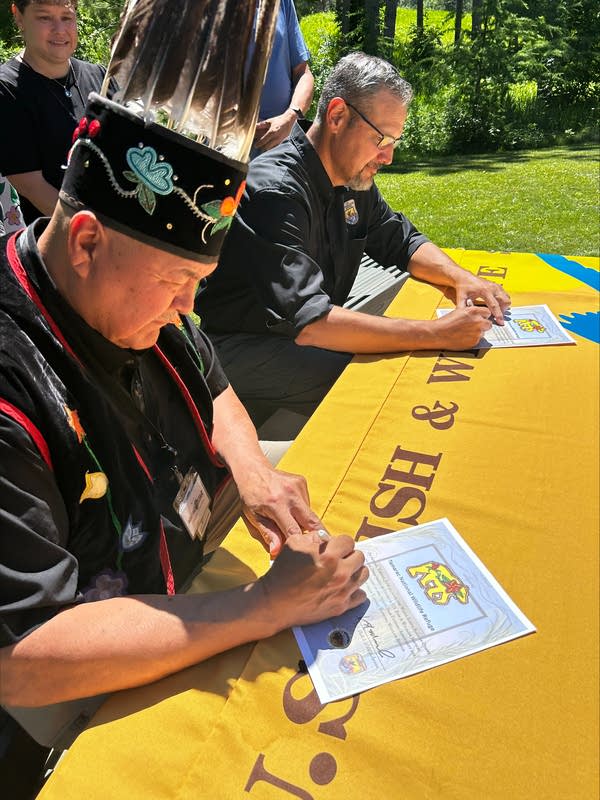 Two people signing documents at a table