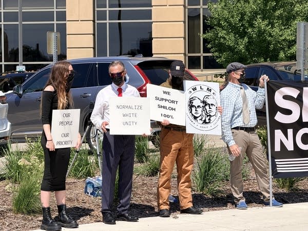 White supremacist protesters hold posterboard signs reading "Our people, our priority" and "Normalize white unity."