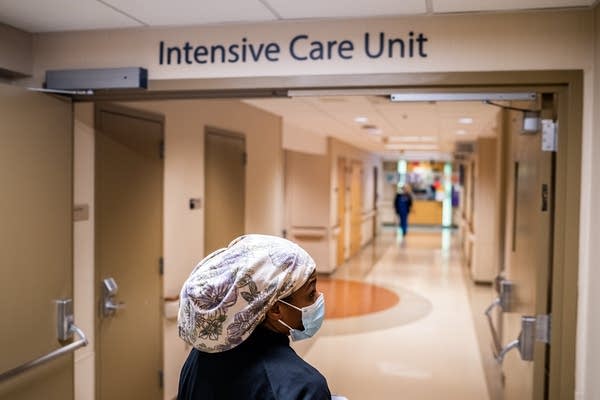 A woman walks down a hallway with an "Intensive Care Unit" sign above her.