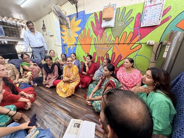 People sit on the floor in front of a mural
