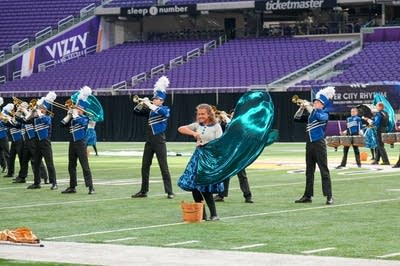 A marching band performs on the field of a football stadium.