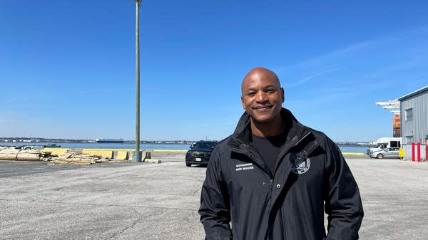 Maryland Governor Wes Moore stands at a port in front of the water.